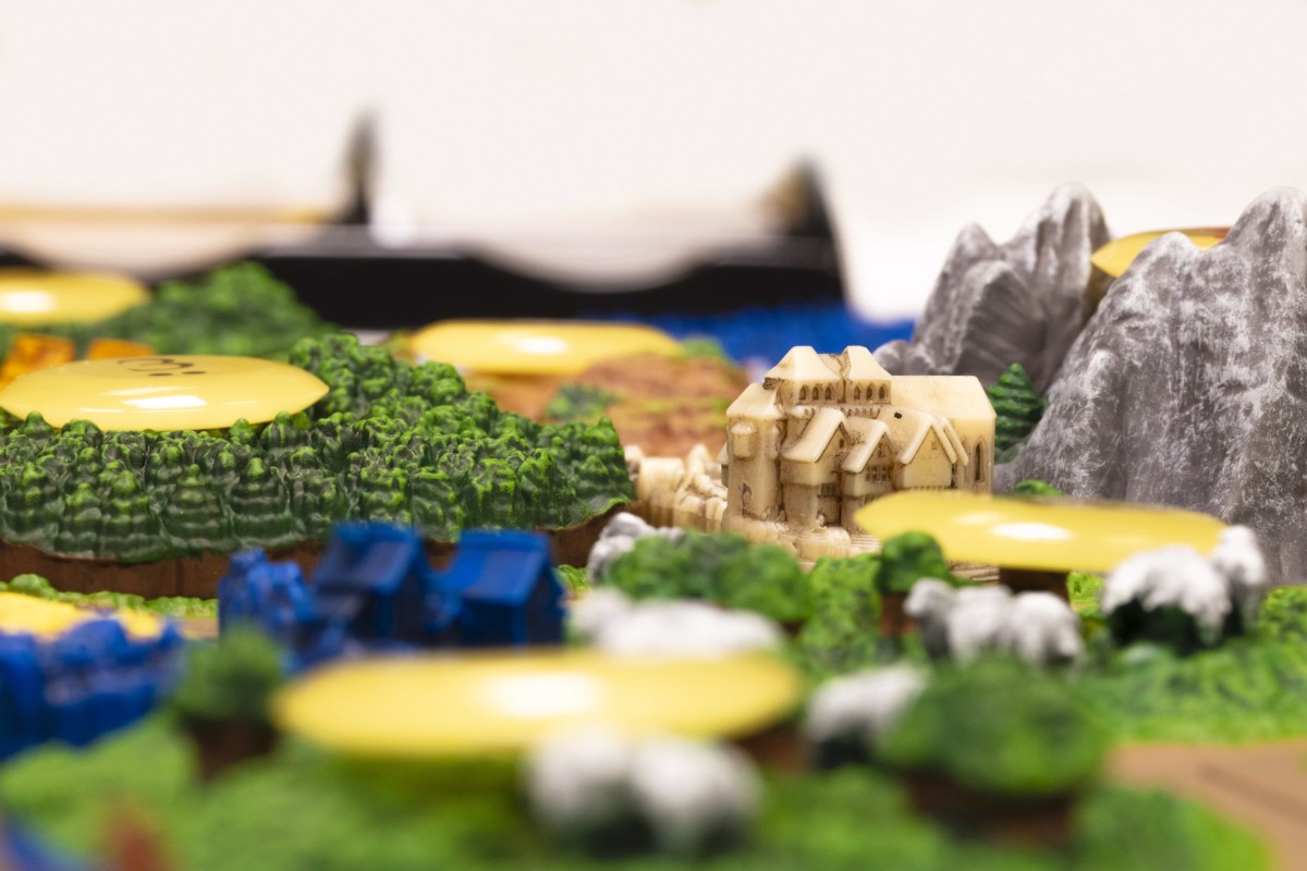 a close-up look of the detailed village and forest pieces for Catan