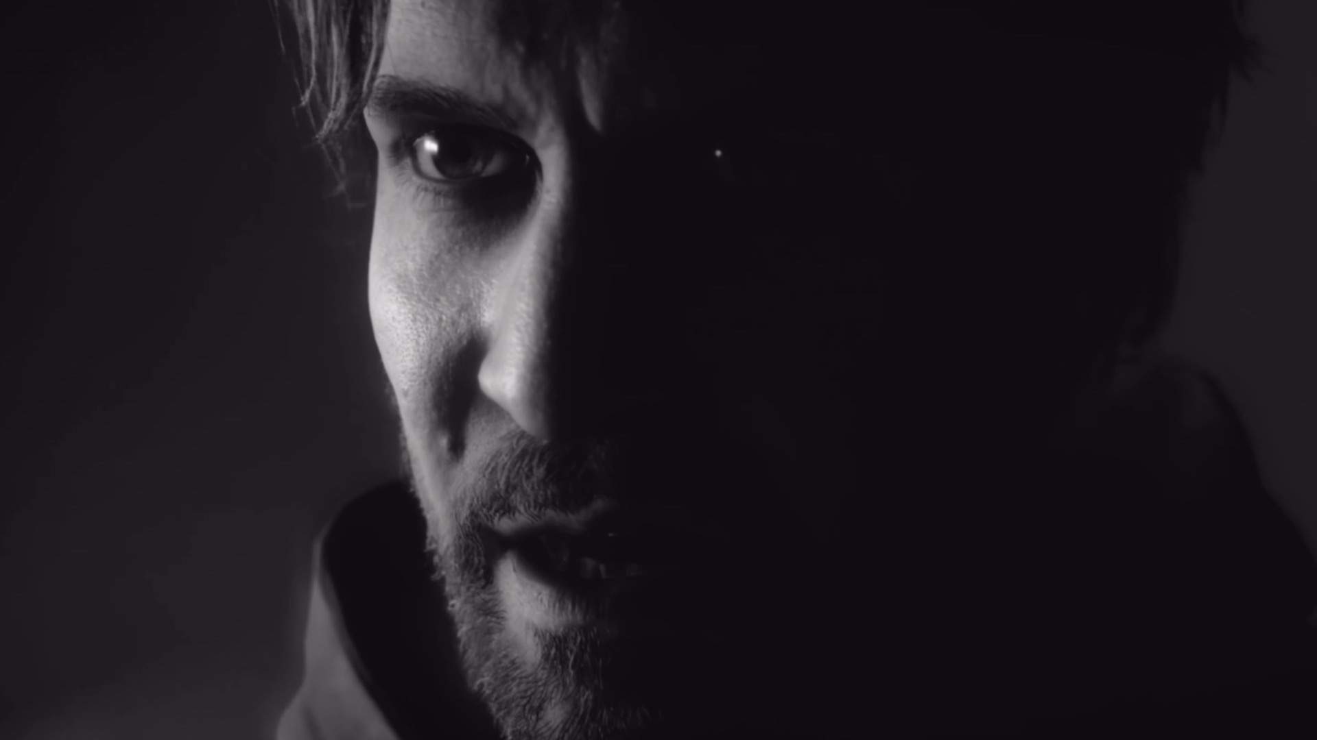 A live-action image of Alan Wake in black in white, shrouded in darkness