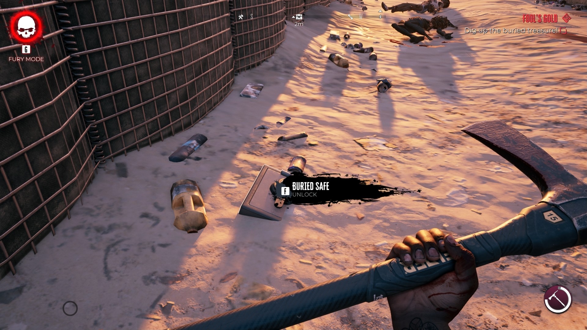 Dead Island 2 screenshot showing a safe buried under the sand, with some dead zombies in the background and a lot of litter lining the ground.