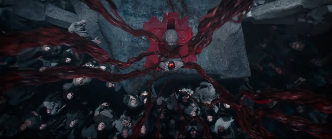 A lich in red robes surrounded by followers holding up an artifact