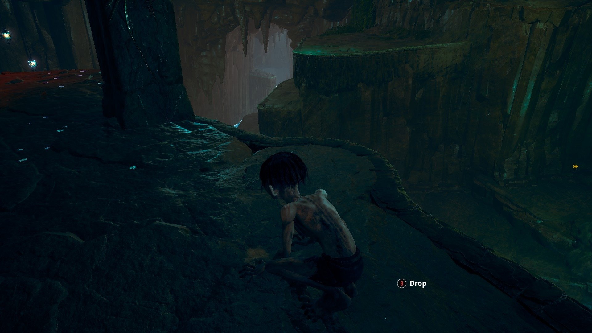 Gollum screenshot showing a wet cavern with a pool at the bottom. Gollum is crouched on a ledge overlooking the water and several platforms below. 