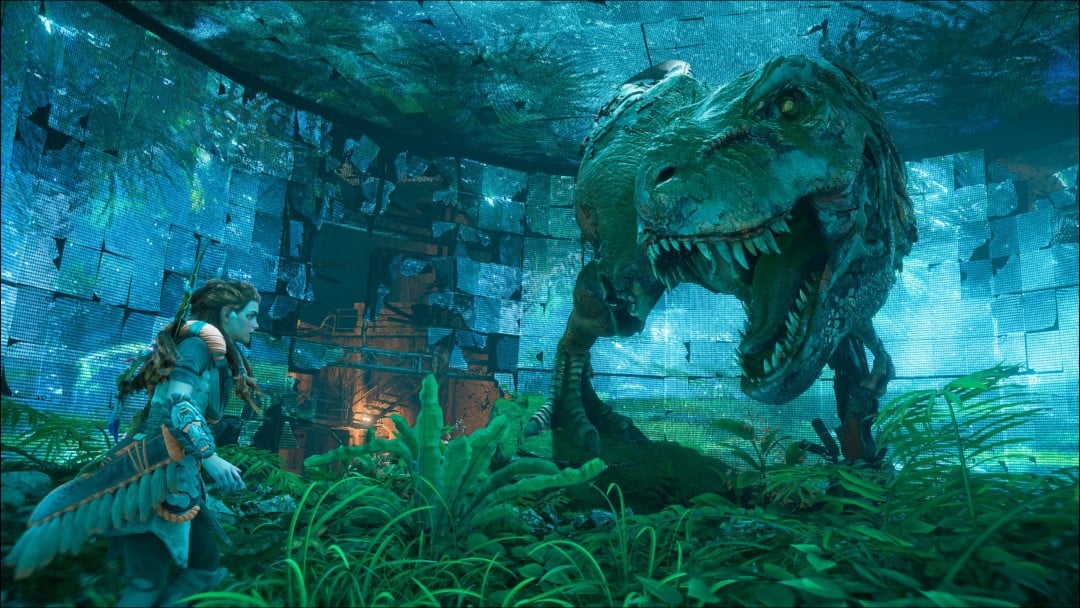 Aloy standing in front of a giant T Rex statue in a ruined movie studio from Horizon Forbidden West: Burning Shores