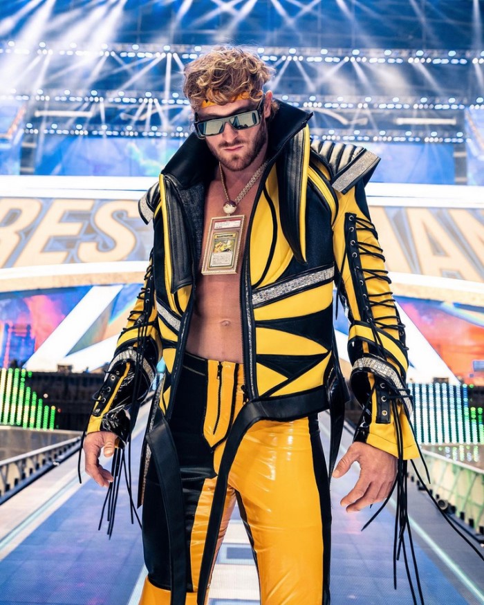 Logan Paul posing in his wrestling outfit, the pikachu card hanging from his neck.