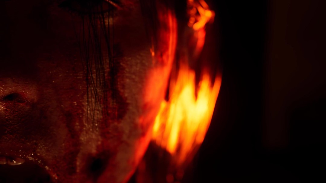A young woman's face in close up, orange flames in the background