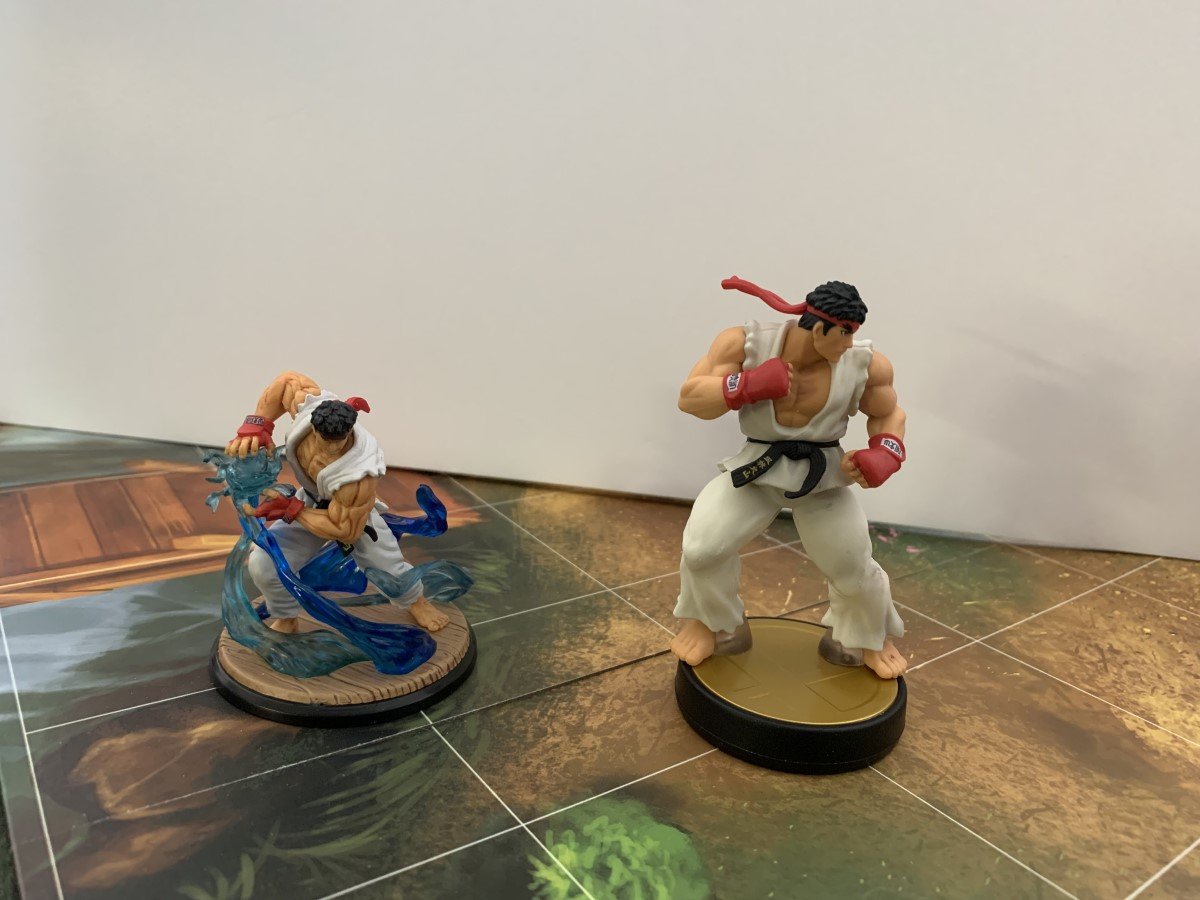 A side by side comparison of Ryu's amiibo figure and his game's miniature