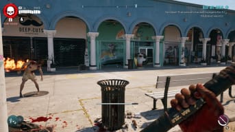 Dead Island 2 screenshot showing an abandoned storefront for a surfboard rental company with a cartoon shark mascot out front and a zombie to the left of the store.