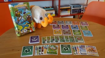 A display of Bugxnax: The Card Game, showing the box, cards, and a Bunger plush.