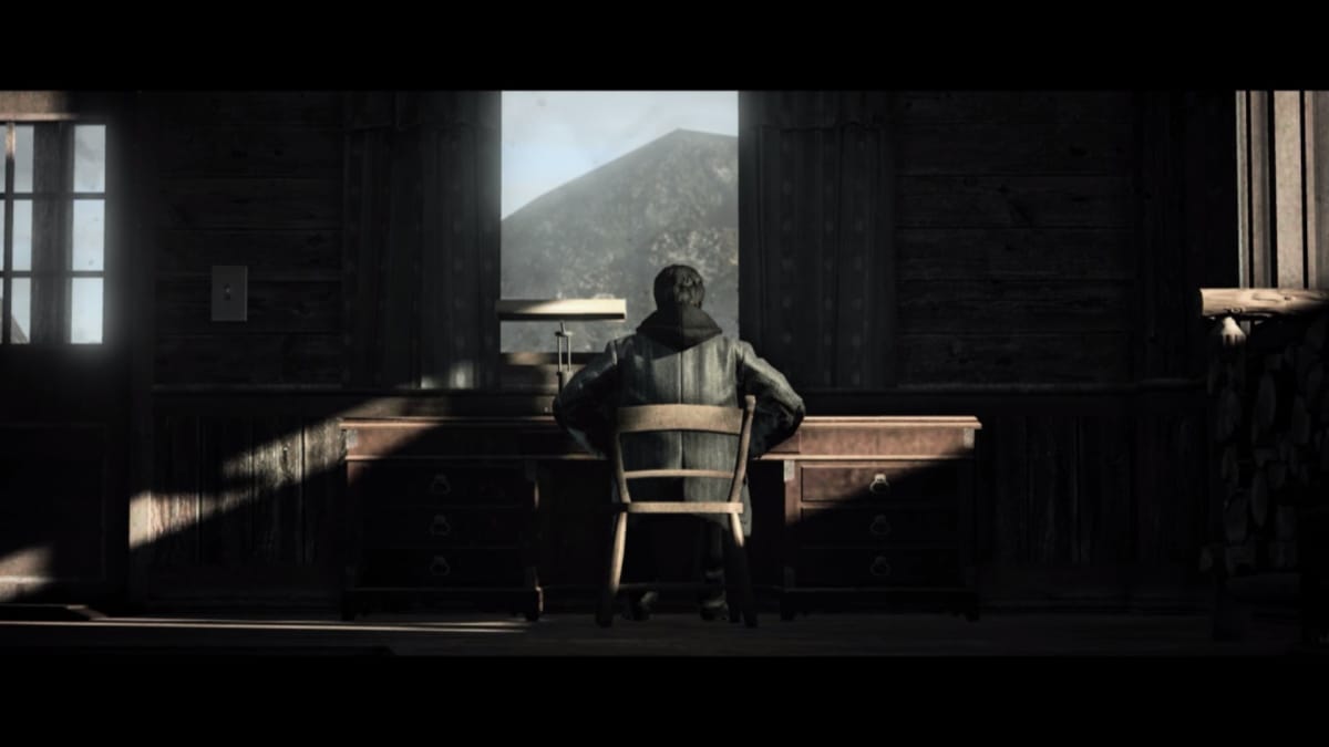 Alan Wake sitting at a large desk, his back to the camera, a mountain is seen in the window.