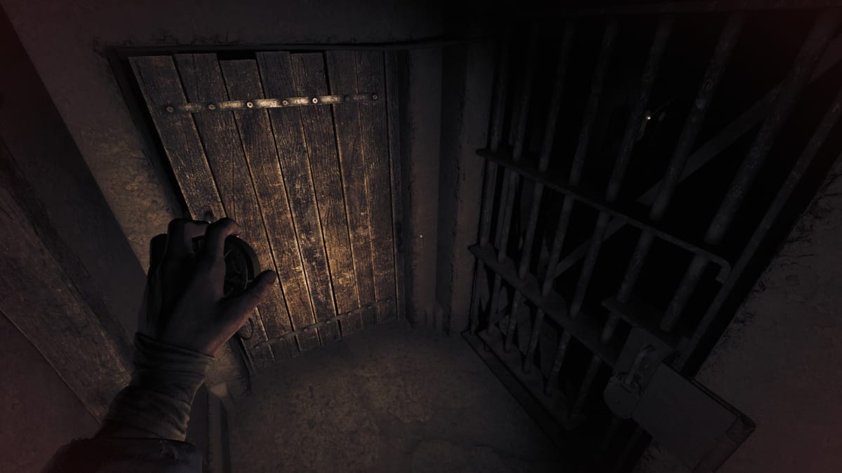 Amnesia: The Bunker screenshot showing a darkly lit cupboard with a metal and wooden door. 