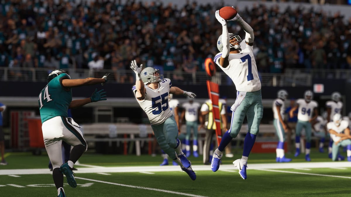 A player leaping up with the ball while another player calls for it in Madden NFL 23