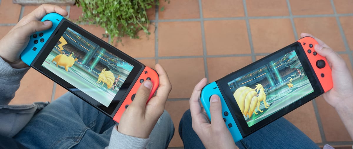 Two people playing Nintendo Switch consoles. Nintendo has also been hit with controller drift lawsuits just like Microsoft