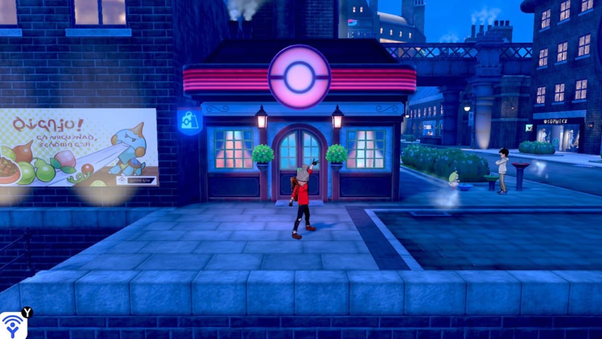 Pokemon Sword and Shield screenshot showing a person standing in front of a Pokecentre in a large town, striking a pose. 
