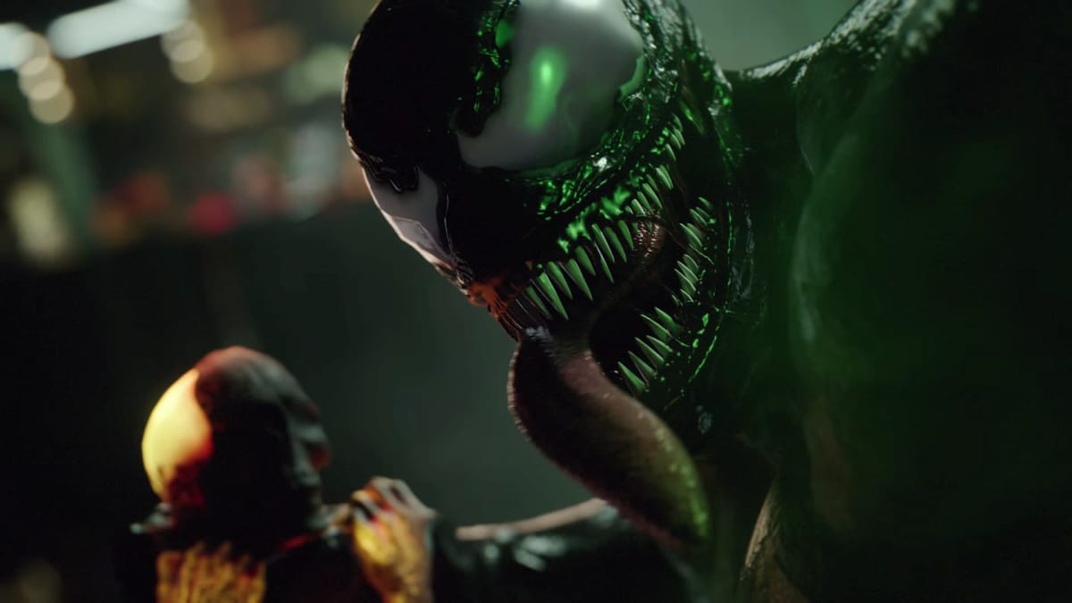 Screenshot of Venom looking at the camera, teeth bared and long demon like tongue sprawled out ready to take his next victim 