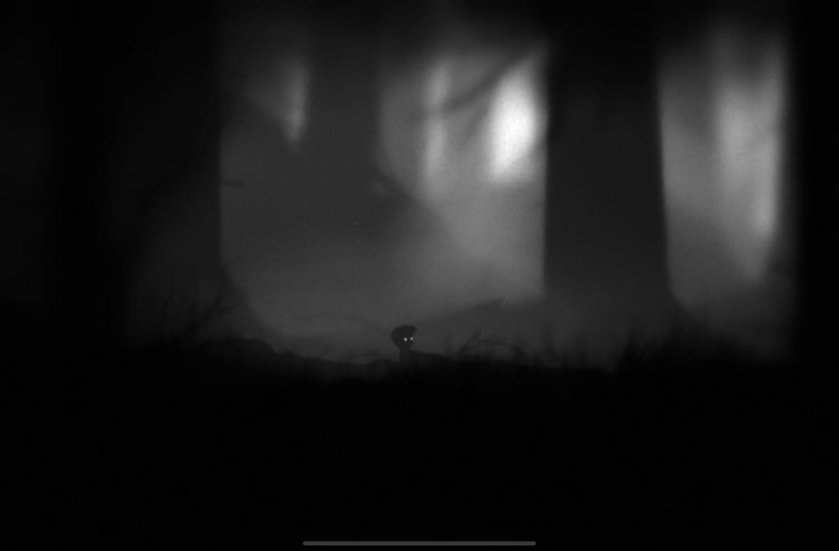The small playable child in LIMBO, one of the best Apple Arcade games, is waking up on the ground.