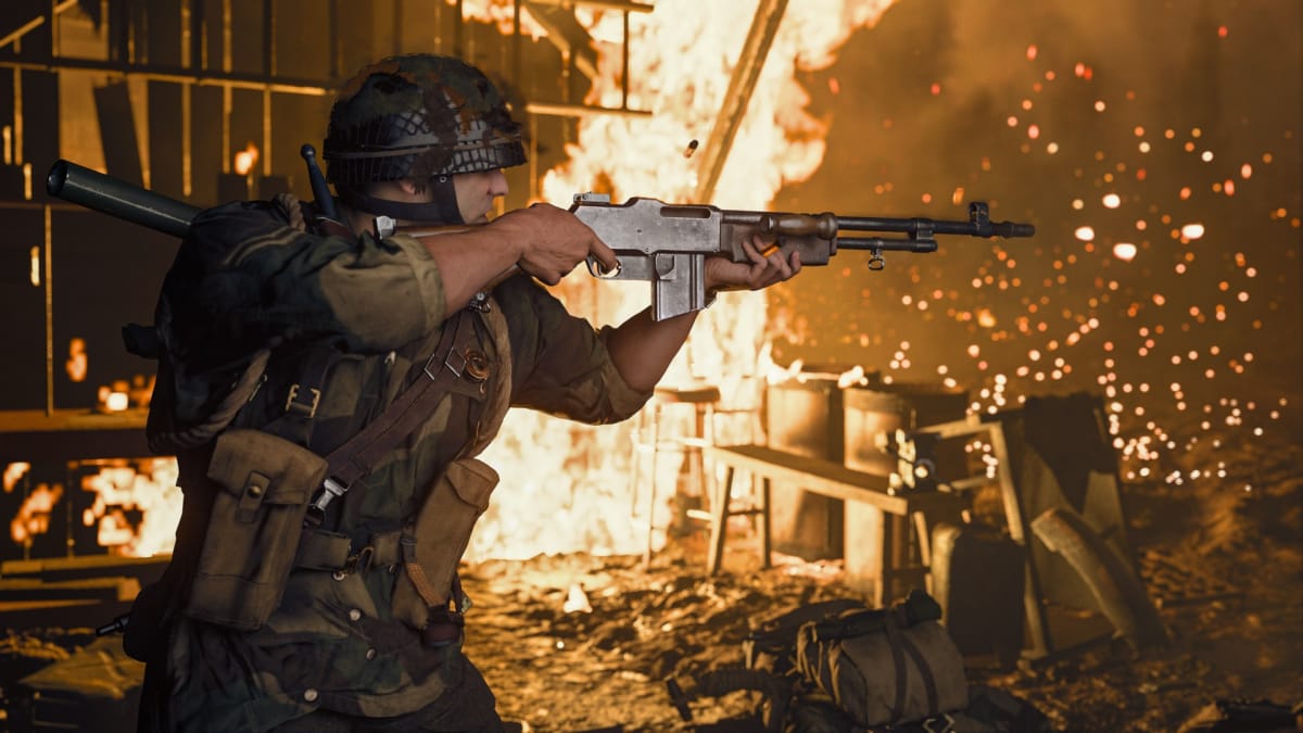 An in-engine screenshot of Call of Duty: Vanguard, showcasing a burly man in a fiery building aiming his BAR assault rifle towards an off-screen target.