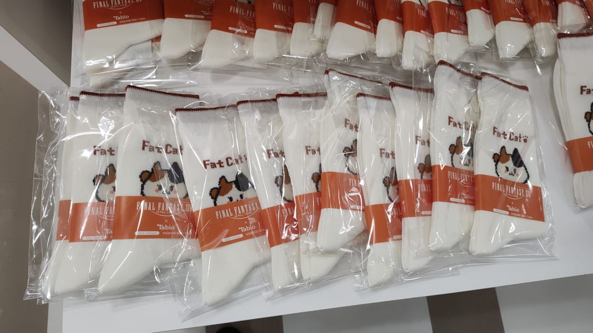A stack of Fat Cat socks by Tobio sits on a display table at the A Decade's End Final Fantasy XIV event