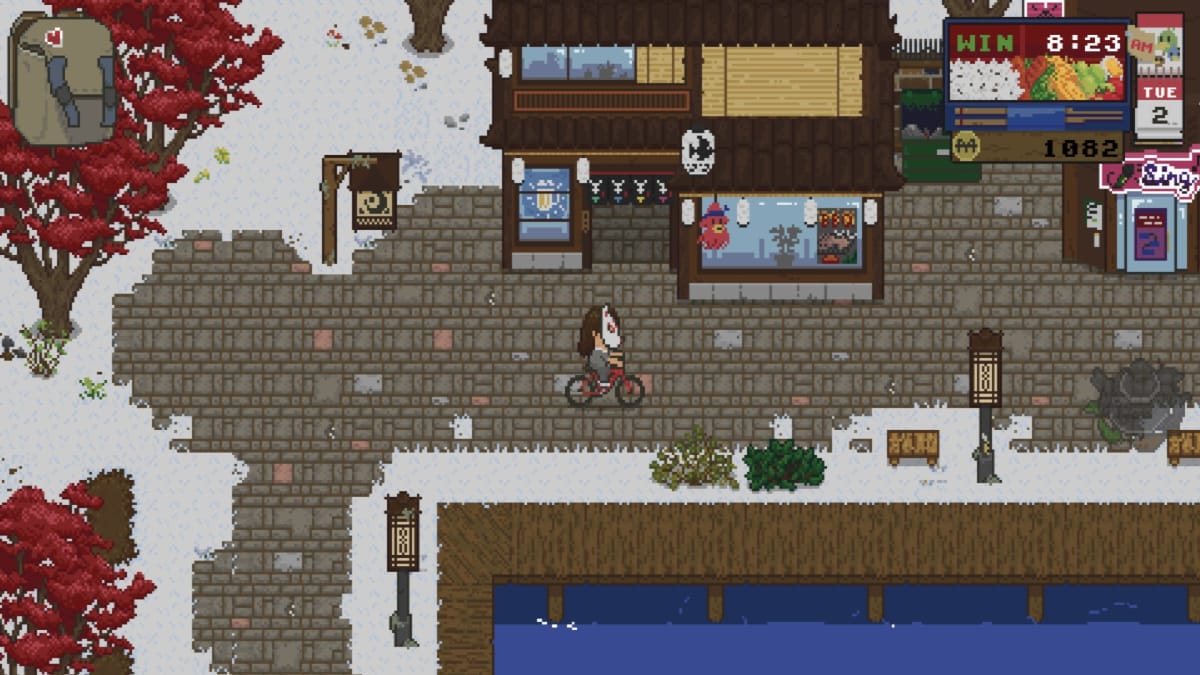 Spirittea screenshot showing a snow-covered town rendered in pixel art style with a mask wearing character riding a red bicycle through the scene