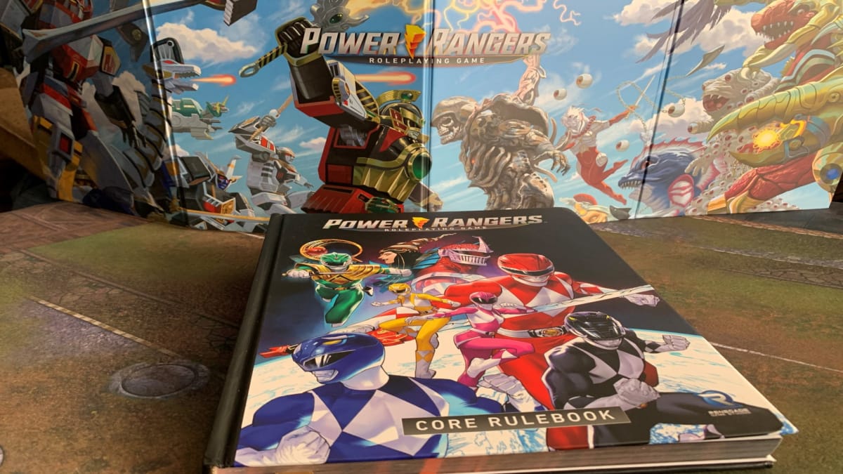 The core rulebook of Power Rangers: The Roleplaying Game, laid out in front of a GM Screen