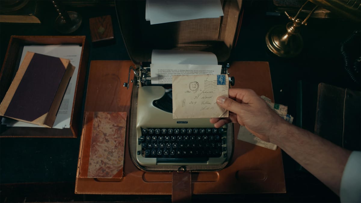 A man holding a letter over a typewriter in Wales Interactive's FMV adventure The Isle Tide Hotel