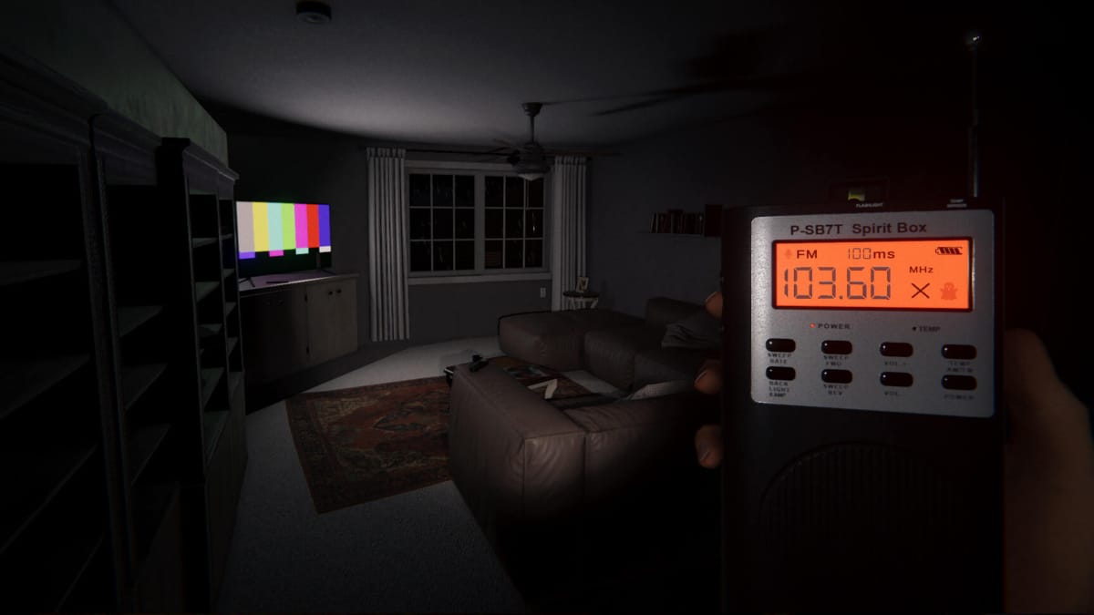 The player holding a Spirit Box tool in a dark room with a switched-on TV in Phasmophobia