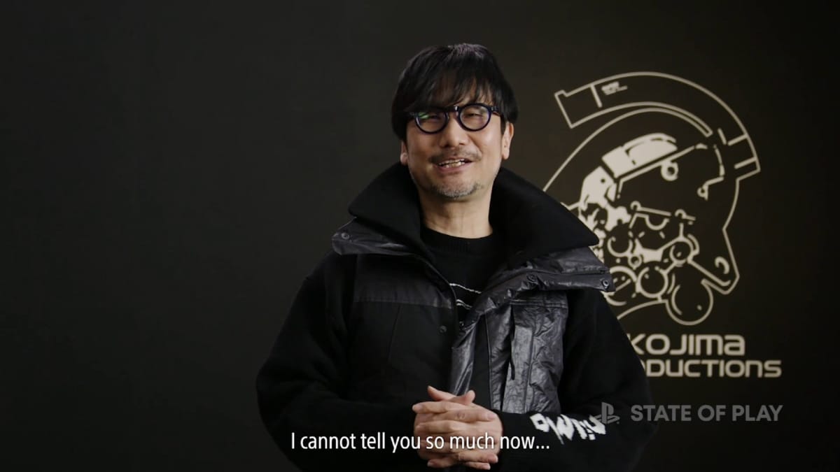 Hideo Kojima, with the captioned text 'I cannot tell you so much now" below him, standing in front of a Kojima productions logo