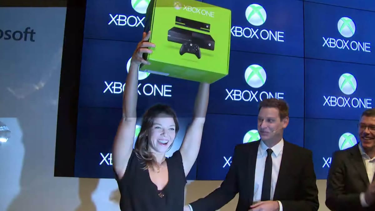 A woman holding an Xbox One box aloft at the Xbox One launch event