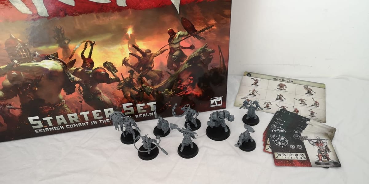 photo showing several plastic figures sitting on a table with a box fo Warcry Iron Golems sitting in the background. 