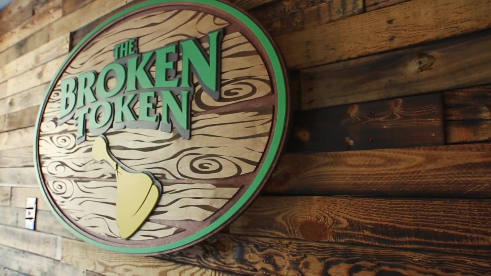 The logo of Broken Token on a wooden plaque hung on a wall