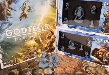 photo showing several boxes for Godtear with various minatures and game boards sitting on the table in front of the boxes