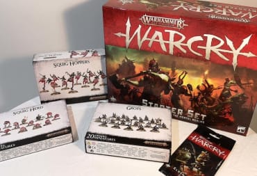 Photo showing a box of Warhammer: Age of Sigmar Warcry mininatures with the miniatures themselves spread out on a table in front of the box. 