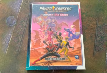 The hardcover of Power Rangers Across The Stars on a gaming mat.