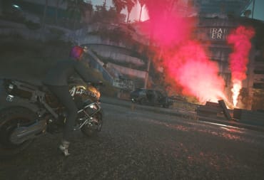 The player rides a motorcycle, while looking at red smoke that denotes the location of an airdrop.