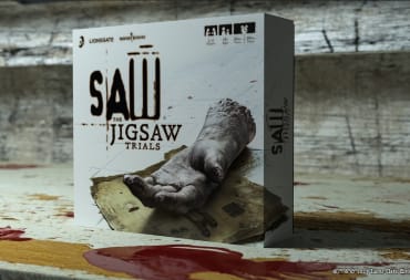 Official Kickstarter box art for Saw: The Jigsaw Trials. The box is on a dirty tile floor with puddles of bright red blood nearby.
