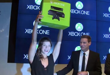 A woman holding an Xbox One box aloft at the Xbox One launch event